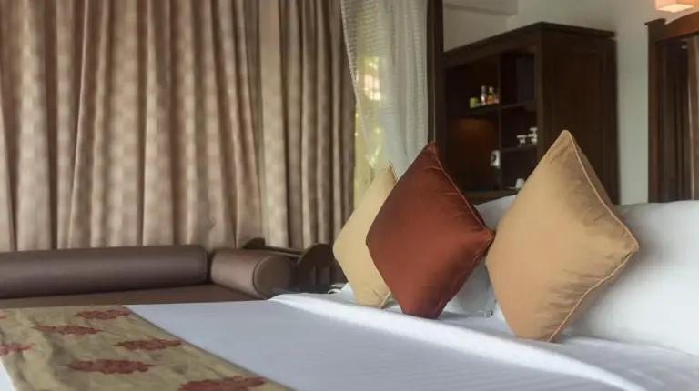 a hotel room with a bed with pillows and a couch at Nora Buri Resort & Spa in Chaweng