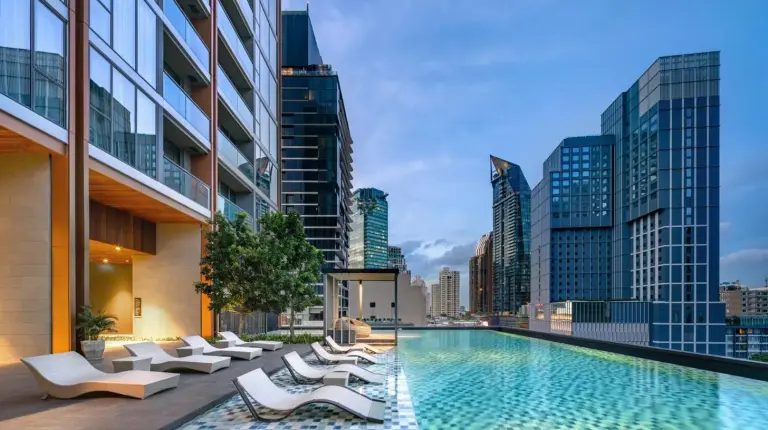 a swimming pool with lounge chairs and a city skyline at Oakwood Suites Bangkok in Bangkok