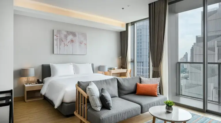 a hotel room with a bed and a couch at Oakwood Suites Bangkok in Bangkok
