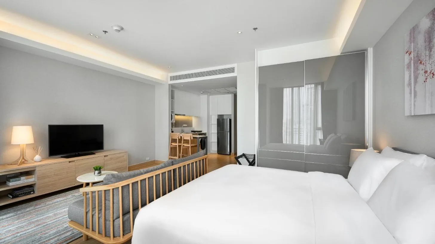 a hotel room with a bed and a television at Oakwood Suites Bangkok in Bangkok