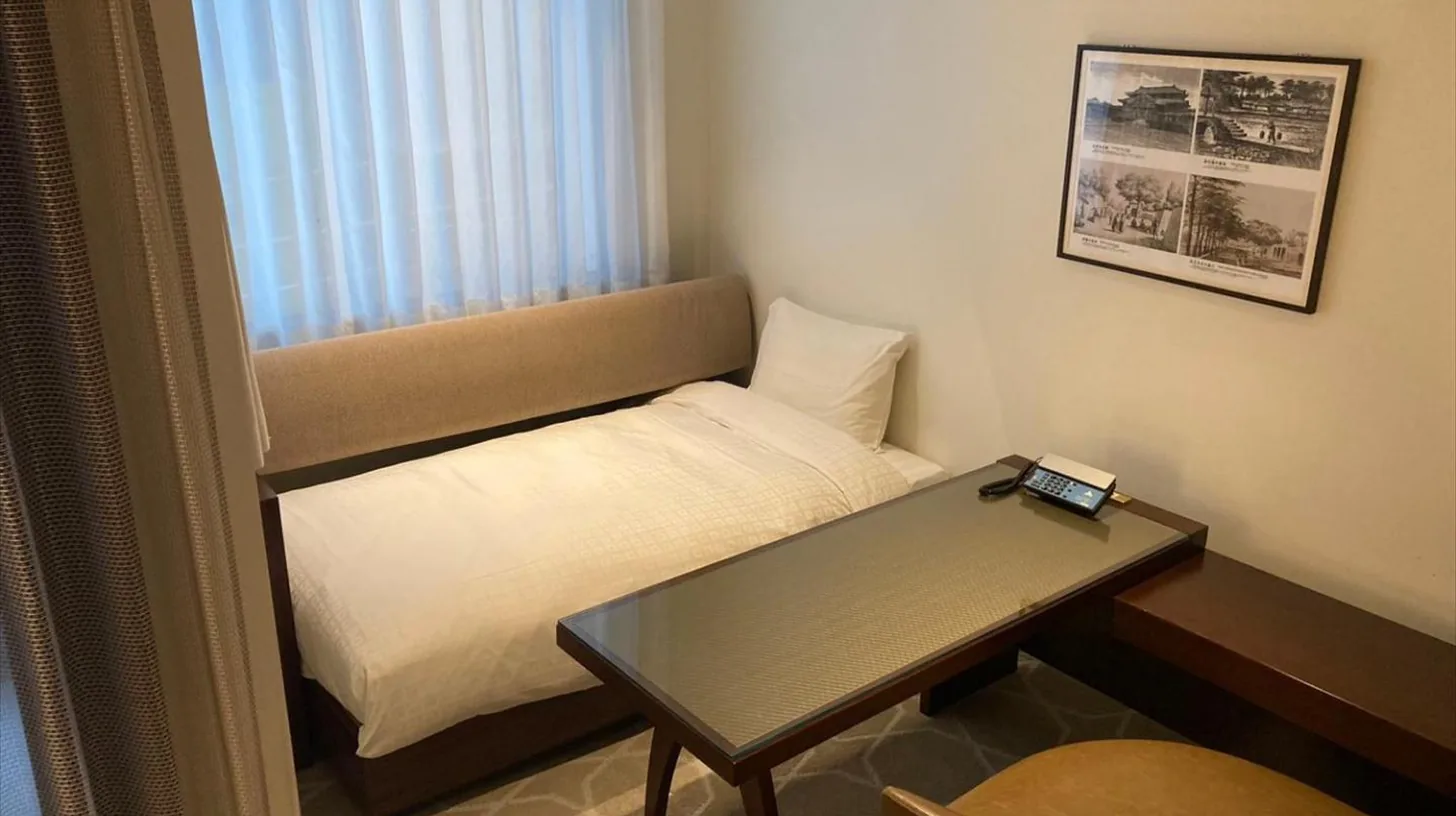 a small room with a bed and a table at Okinawa EXES Naha in Naha