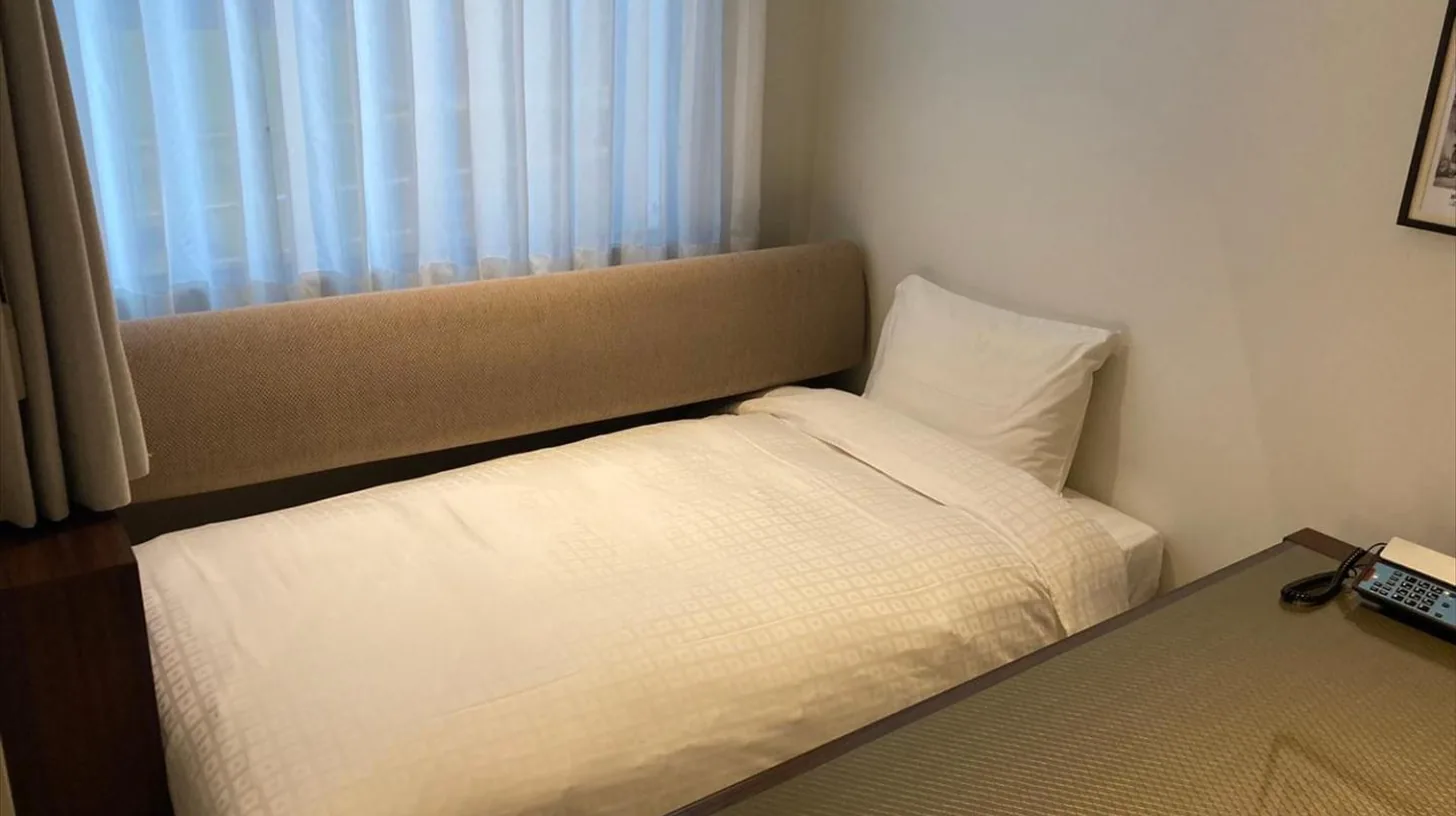 a small bedroom with a bed and a window at Okinawa EXES Naha in Naha