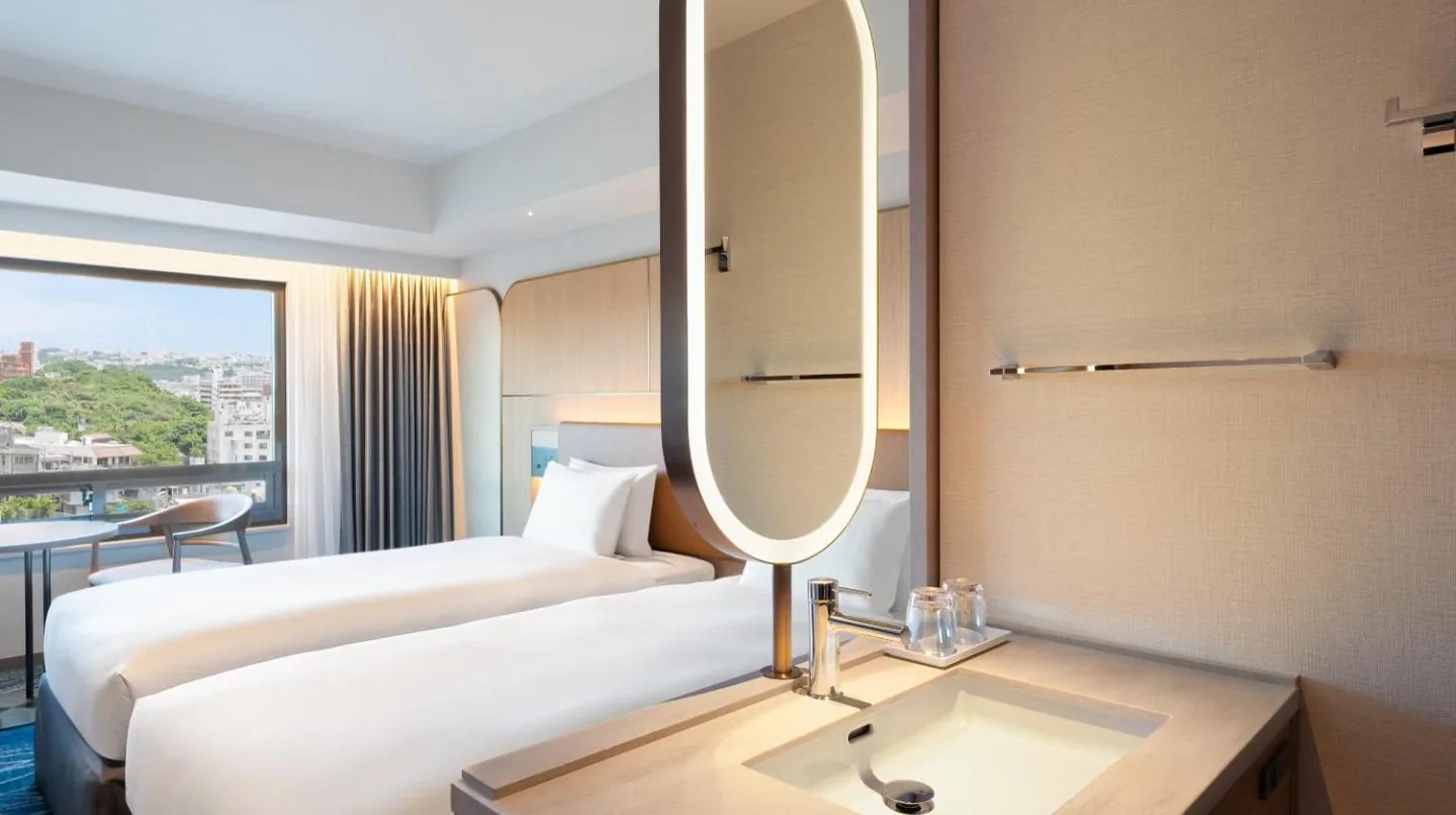 a hotel room with a bed and a sink and a mirror at Okinawa Harborview Hotel in Naha