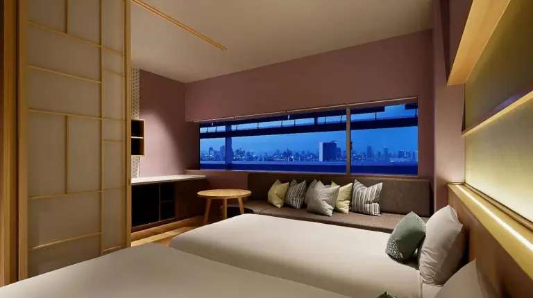 a room with a bed and a table with two glasses of wine at OMO7 Osaka by Hoshino Resorts in Osaka
