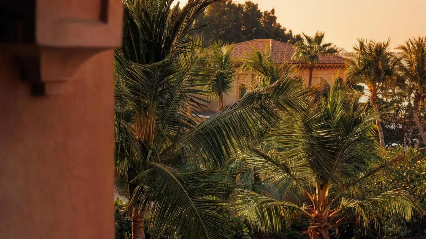 a group of palm trees in front of a building at One&Only The Palm Dubai in Dubai