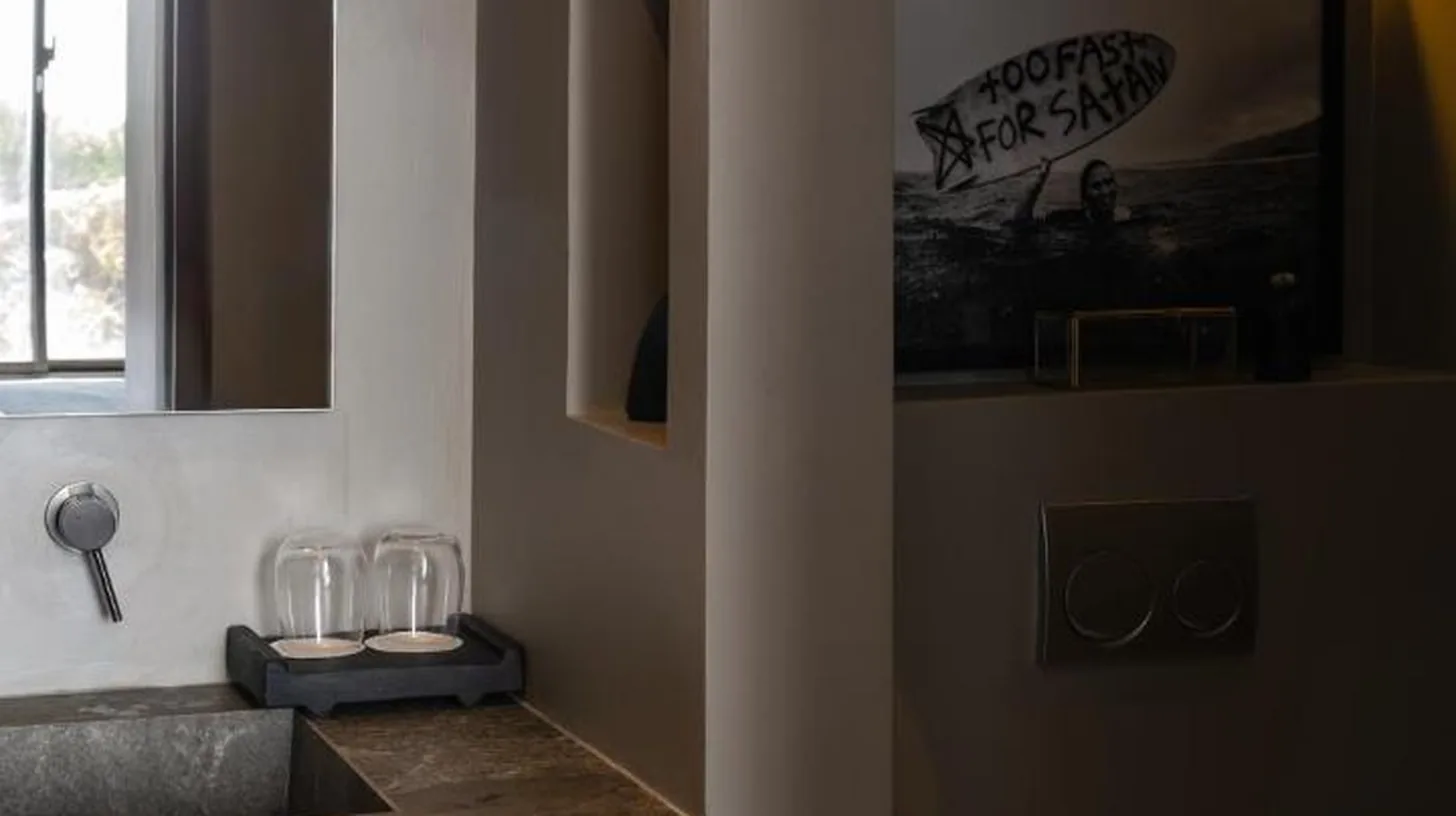 a room with a brick wall with a table and chairs at Orama Bali in Uluwatu