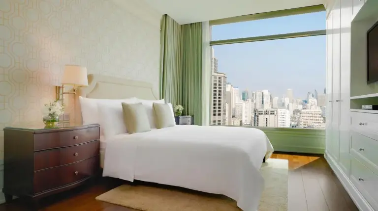 una habitación con una cama blanca y una gran ventana en Oriental Residence Bangkok en Bangkok
