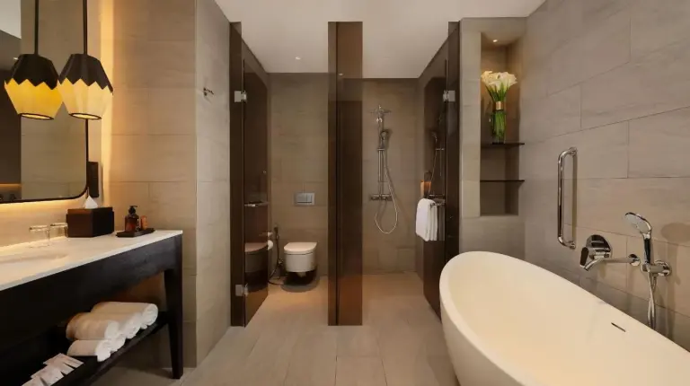 a bathroom with a tub and a sink and a toilet at Padma Hotel Semarang in Semarang