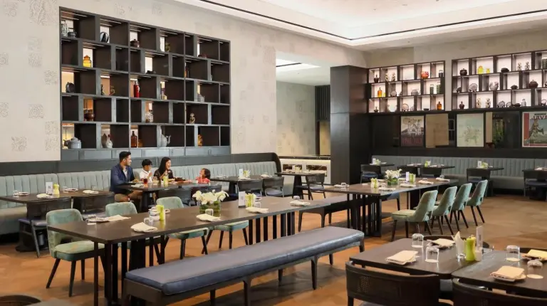 a dining room with tables and chairs and people eating at Padma Hotel Semarang in Semarang