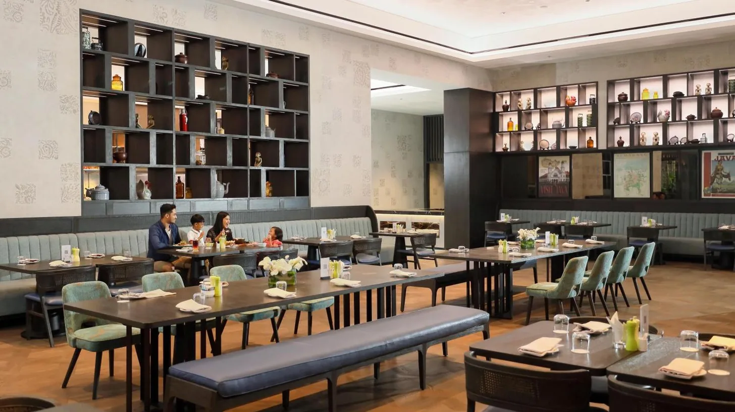 a dining room with tables and chairs and people eating at Padma Hotel Semarang in Semarang