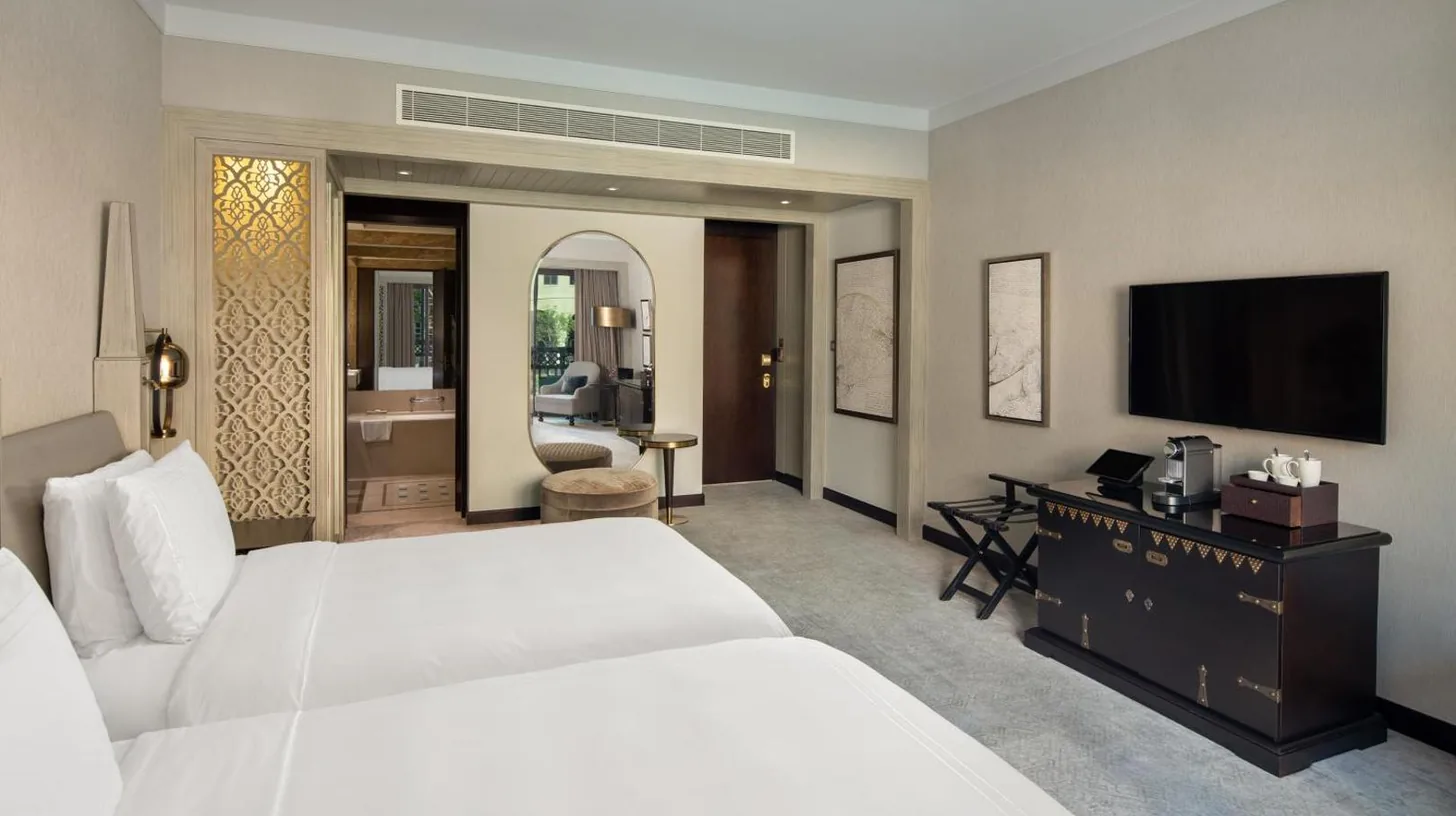 a bedroom with a large white bed and a flat screen tv at Palace Downtown in Dubai