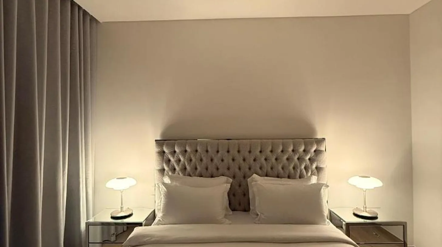Ein Schlafzimmer mit großem weißem Bett und zwei Lampen im Palace Dubai Creek Harbour Residences Skyline Apartment in Dubai