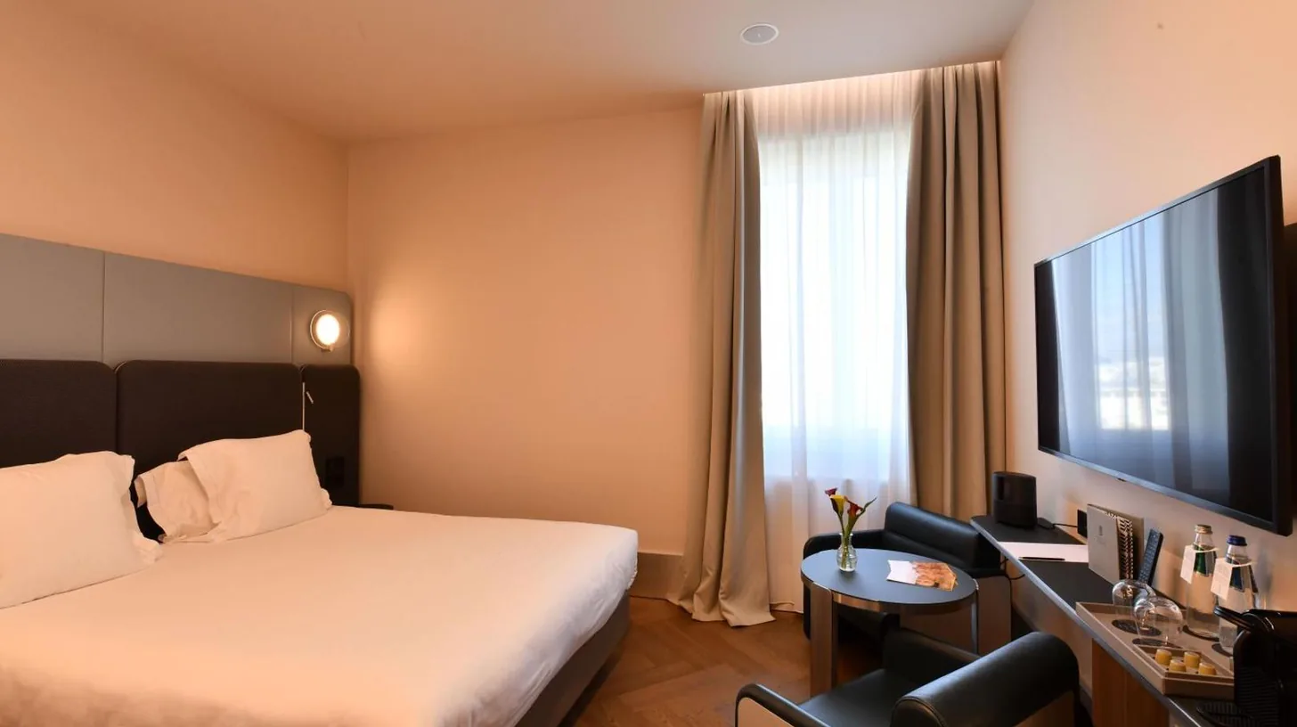 a hotel room with a bed and a flat screen tv at Palazzo Tirso MGallery Cagliari in Cagliari