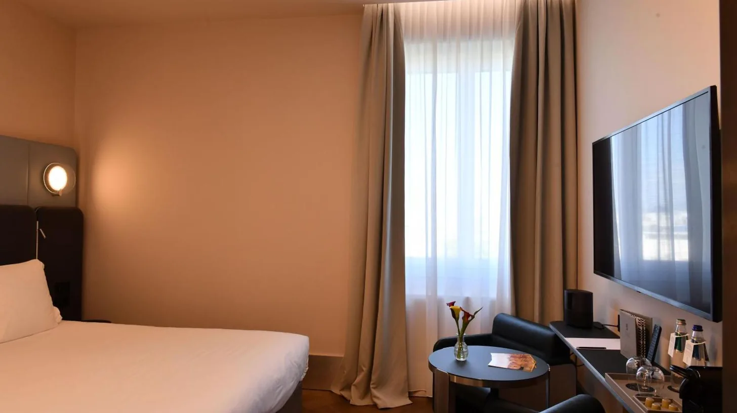 a hotel room with a bed and a desk and a tv at Palazzo Tirso MGallery Cagliari in Cagliari