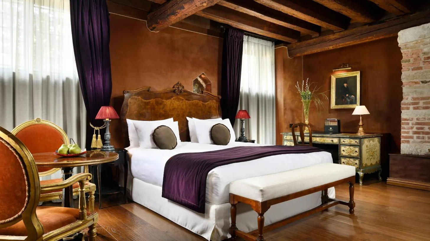a bedroom with a large bed and a table and chairs at Palazzo Venart Luxury Hotel in Venice