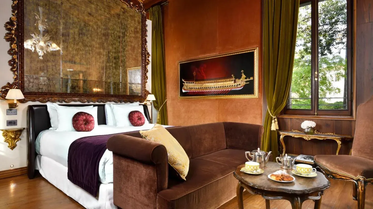 a bedroom with a bed and a chair and a mirror at Palazzo Venart Luxury Hotel in Venice