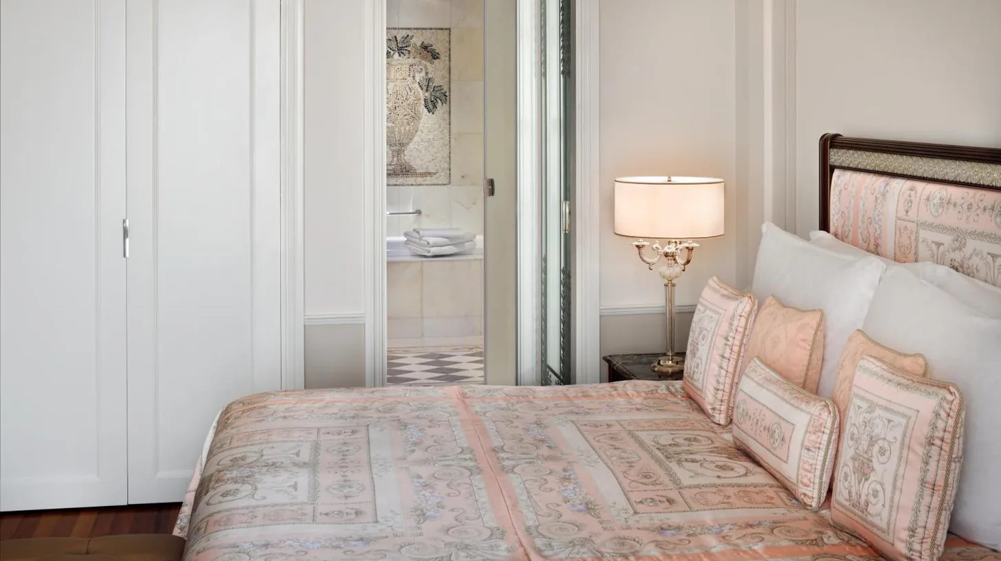 a bedroom with a bed with blue sheets and a window at Palazzo Versace Dubai in Dubai