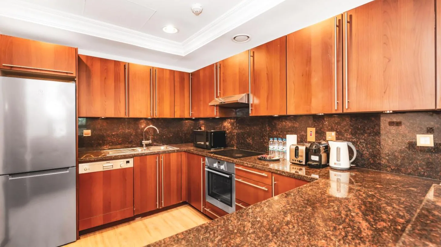 a kitchen with wooden cabinets and stainless steel appliances at Palm Jumeirah Beach Paradise at Fairmont Residence in Dubai