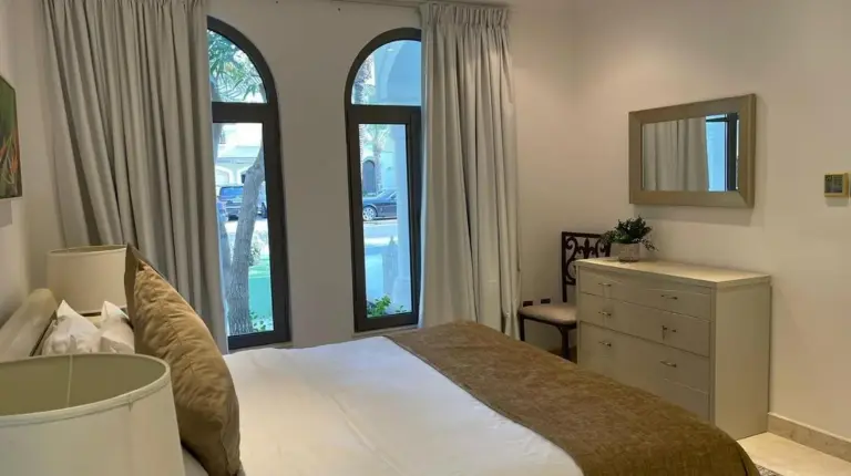 ein Schlafzimmer mit einem Bett und einer Kommode und Fenstern in Palm Jumeirah Strandvilla mit privatem Pool, 5 Schlafzimmer & 1 Hausangestelltenzimmer und Strandzugang in Dubai