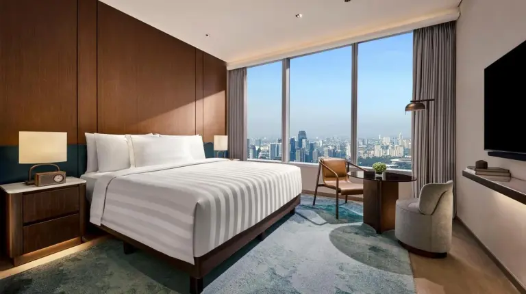 a hotel room with a bed and a large window at Pan Pacific Jakarta in Jakarta