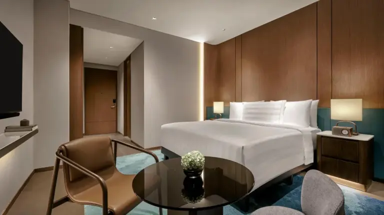 a hotel room with a bed and a table and chairs at Pan Pacific Jakarta in Jakarta