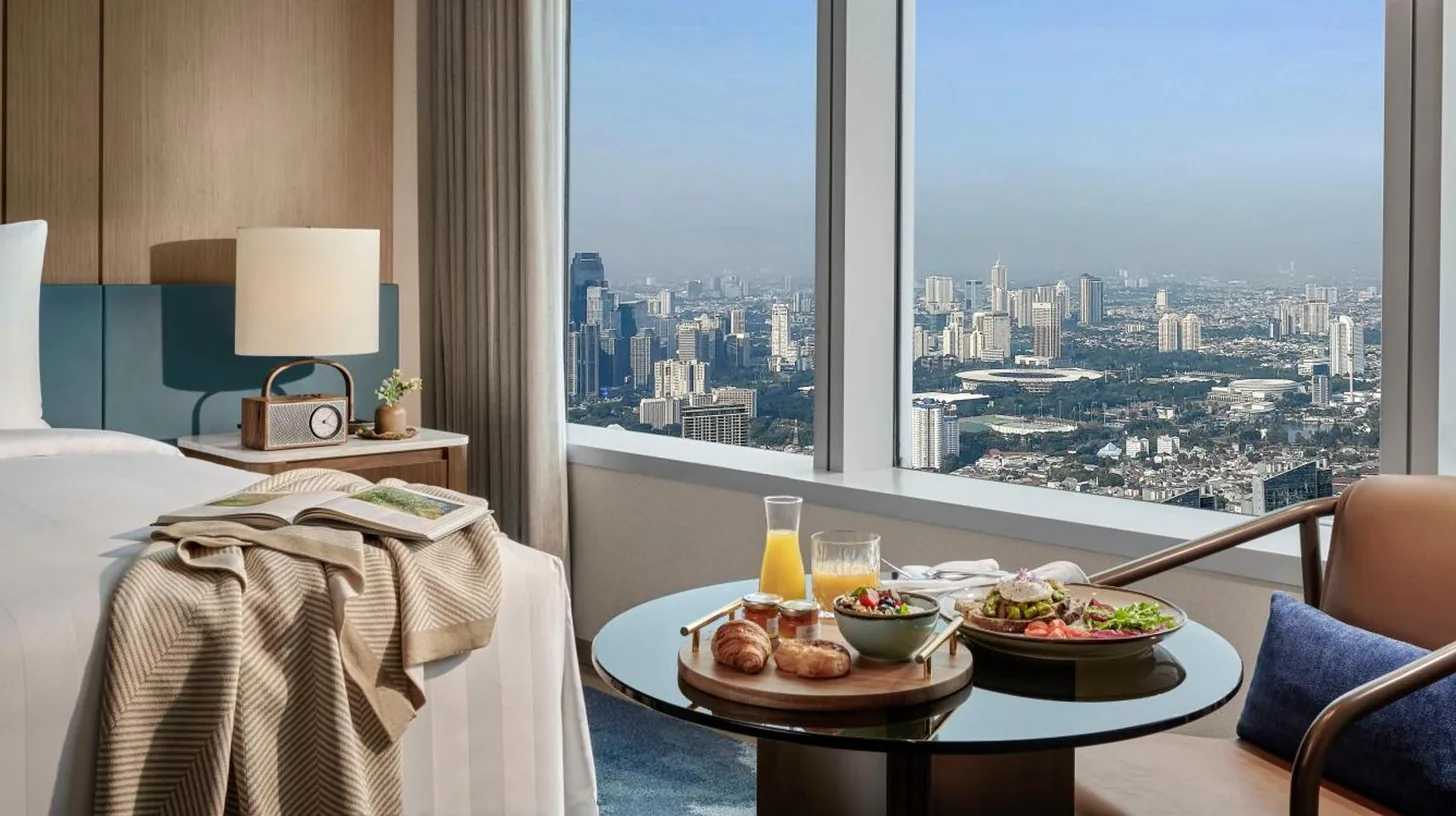 a bedroom with a large bed and a living room at Pan Pacific Jakarta in Jakarta