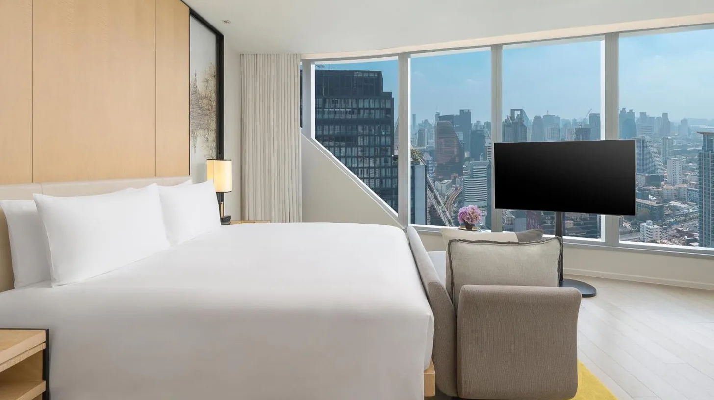 a hotel room with a bed and a chair and a television at Park Hyatt Bangkok in Bangkok