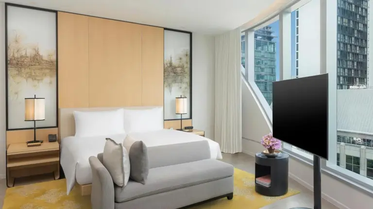 a bedroom with a bed and a chair and a tv at Park Hyatt Bangkok in Bangkok