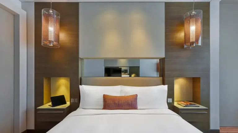 a bedroom with a large white bed and two lights at Park Rotana Abu Dhabi in Abu Dhabi