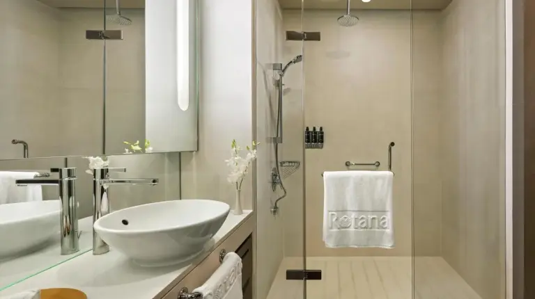 a white bathroom with a sink and a shower at Park Rotana Abu Dhabi in Abu Dhabi