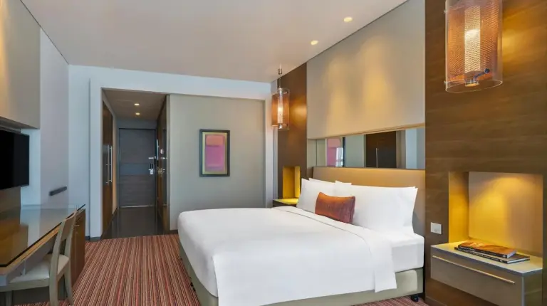 a bedroom with a large white bed and a desk at Park Rotana Abu Dhabi in Abu Dhabi