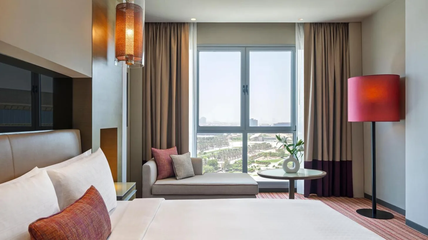 a hotel room with a bed and a chair and a window at Park Rotana Abu Dhabi in Abu Dhabi