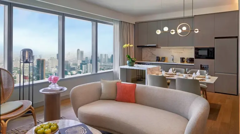 a living room with a couch and a kitchen at PARKROYAL Serviced Suites Jakarta in Jakarta