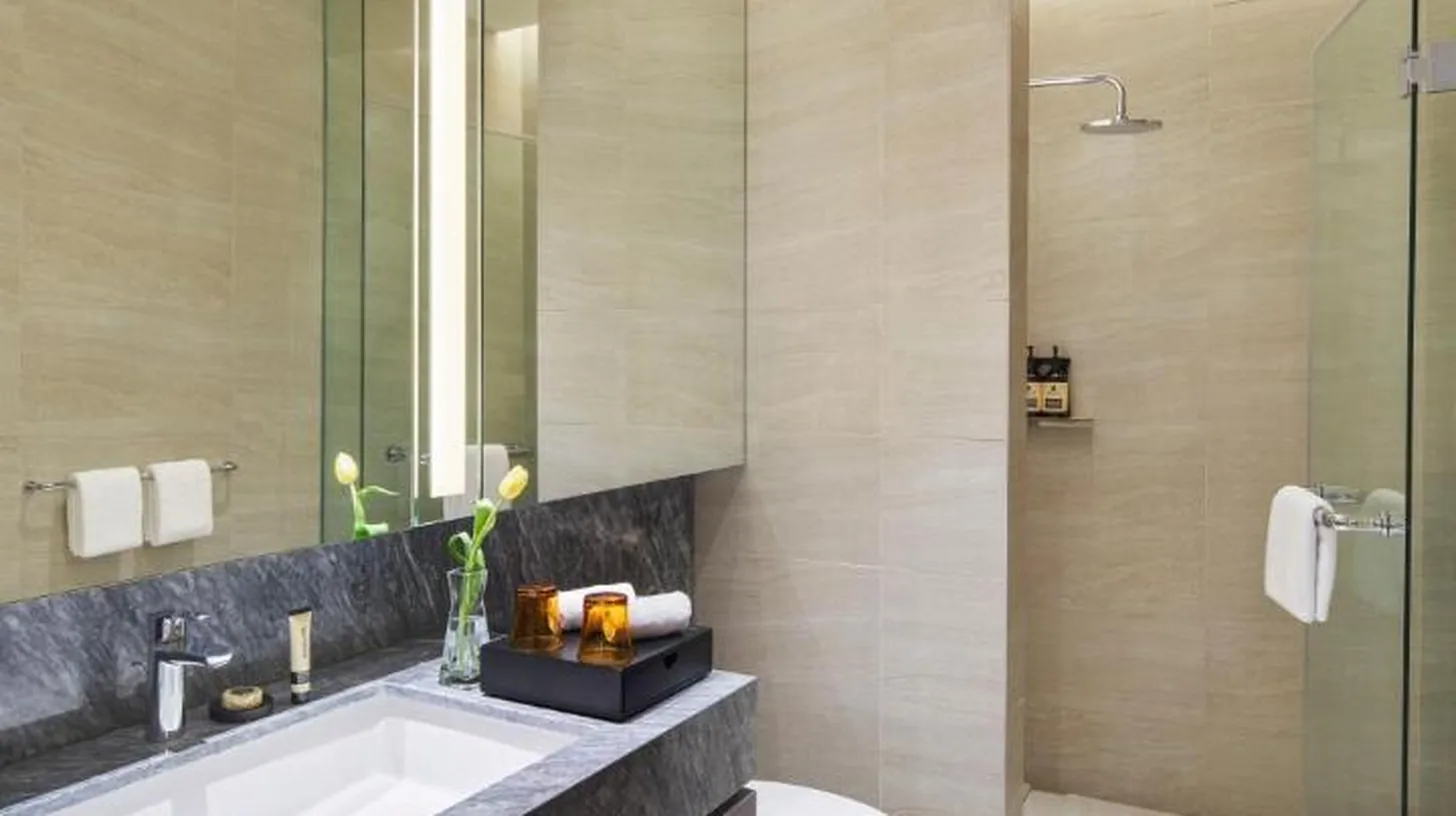 a bedroom with a large white bed and a large window at PARKROYAL Serviced Suites Jakarta in Jakarta