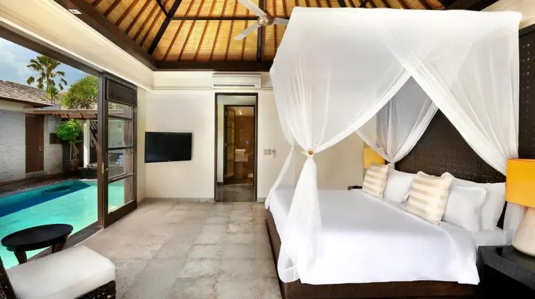 a bedroom with a white bed with a canopy at Peppers Seminyak in Seminyak