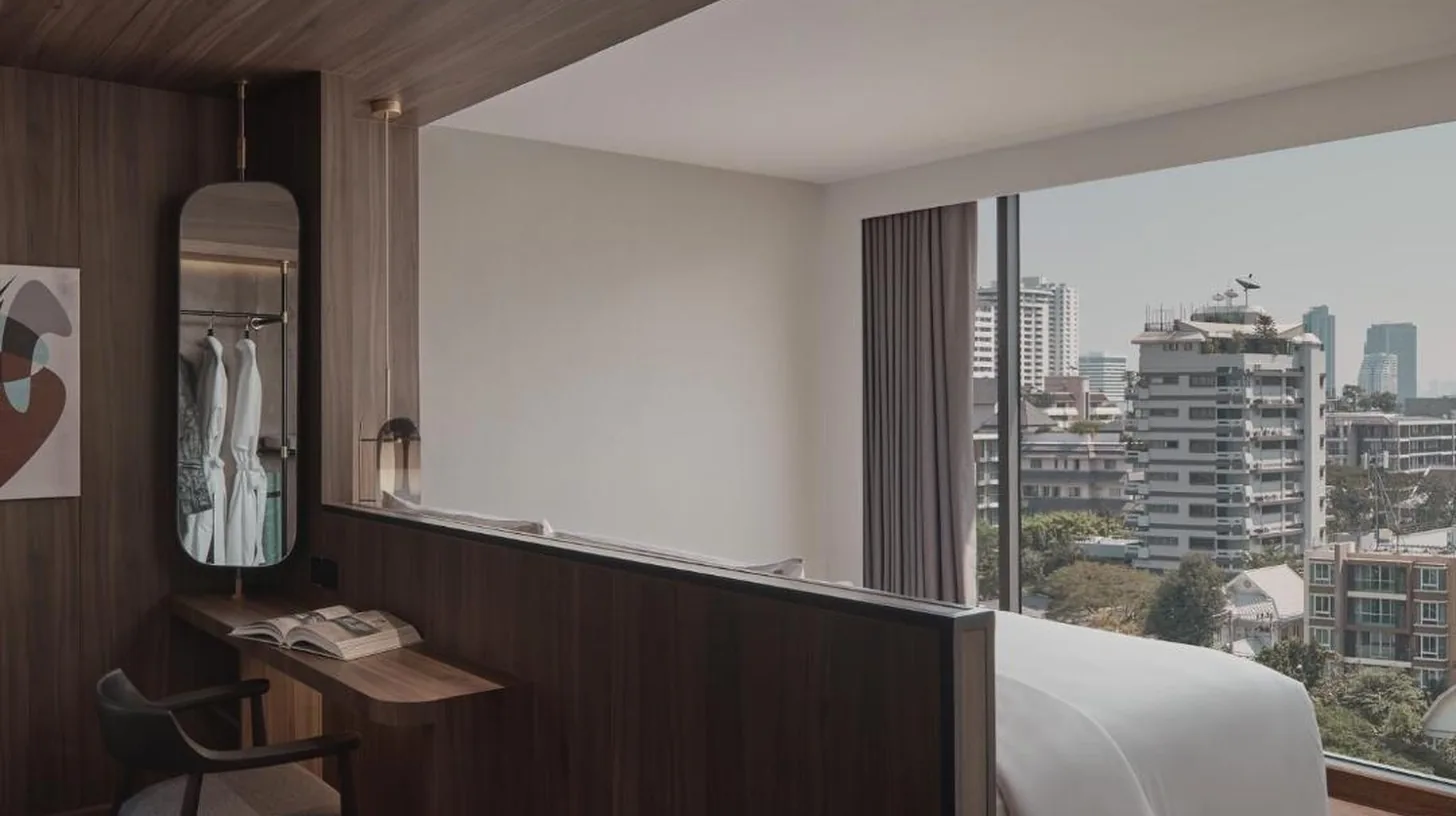 a bedroom with a bed and a desk and a window at Public House Bangkok