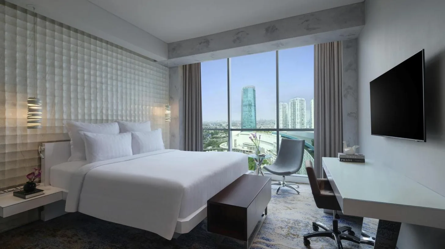 a hotel room with a bed and a desk and a computer at Pullman Jakarta Central Park in Jakarta