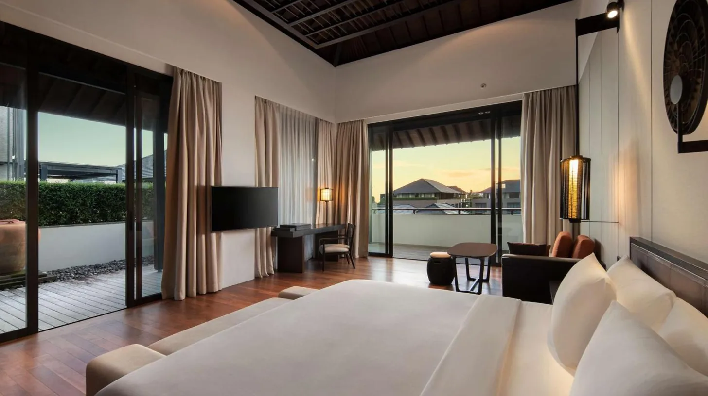 a bedroom with a large bed and a living room at Radisson Blu Resort & Villas Bali Uluwatu in Uluwatu