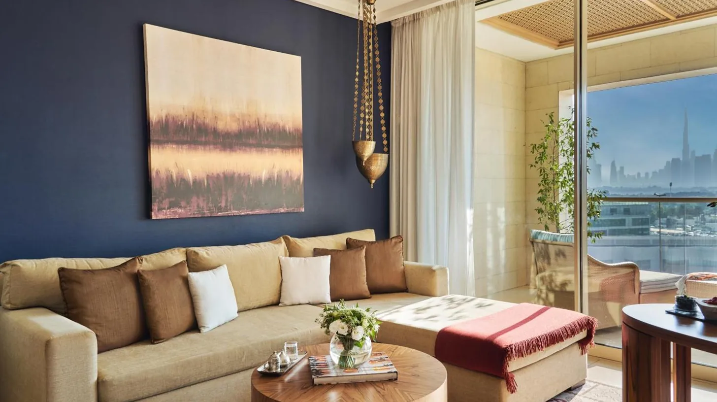 a hotel room with a bed and a living room at Raffles Dubai in Dubai