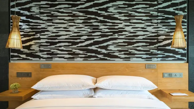 Un lit avec deux oreillers et une peinture au mur au Renaissance Bali Uluwatu Resort & Spa à Uluwatu