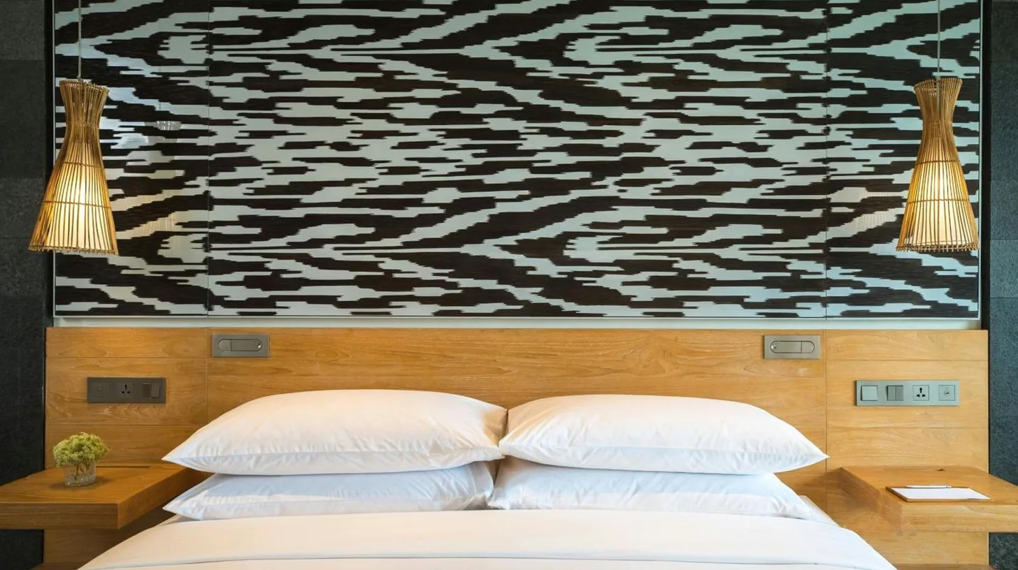 Un lit avec deux oreillers et une peinture au mur au Renaissance Bali Uluwatu Resort & Spa à Uluwatu
