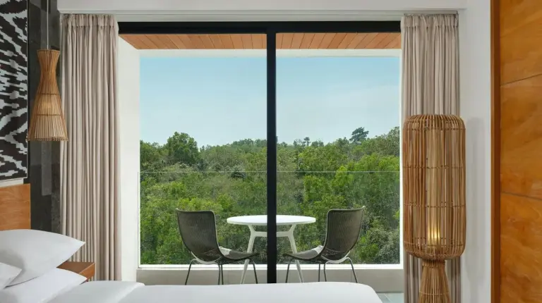 Une chambre avec une grande fenêtre, une table et des chaises au Renaissance Bali Uluwatu Resort & Spa à Uluwatu