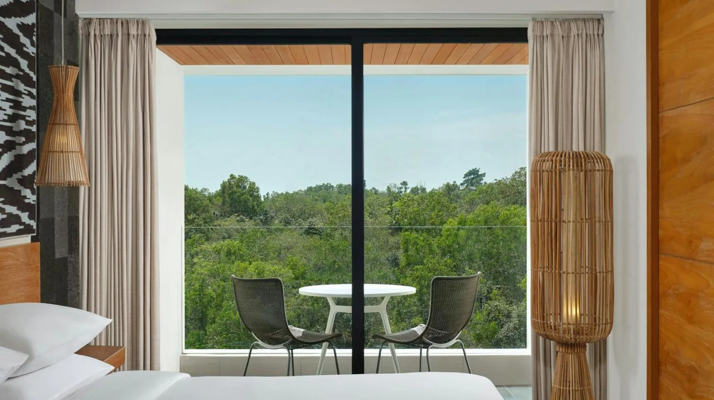 Une chambre avec une grande fenêtre, une table et des chaises au Renaissance Bali Uluwatu Resort & Spa à Uluwatu
