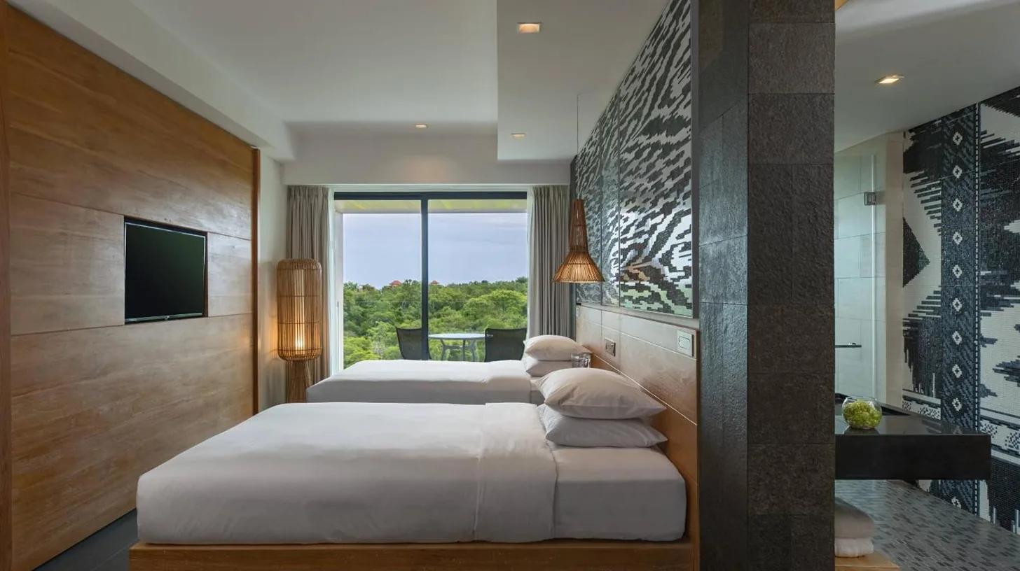Deux lits dans une chambre d'hôtel avec une télévision au Renaissance Bali Uluwatu Resort & Spa à Uluwatu