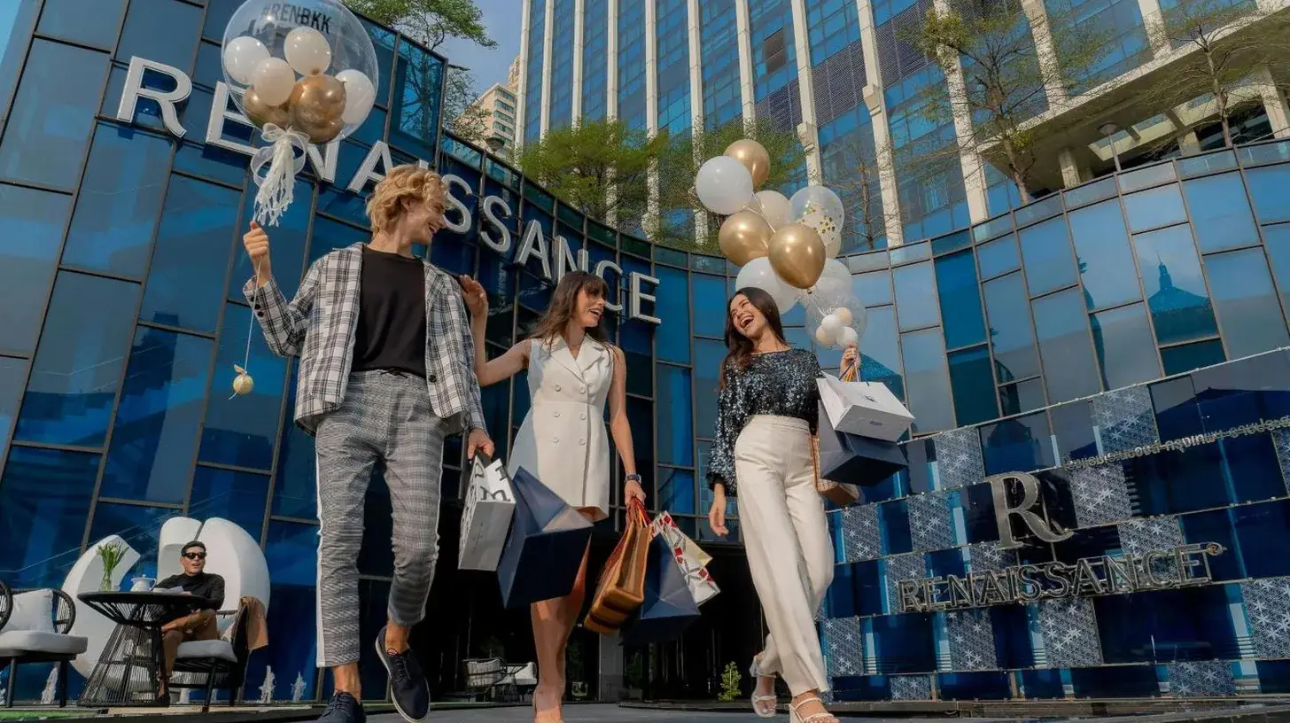 three people walking in front of a building with balloons at Renaissance Bangkok Ratchaprasong Hotel in Bangkok
