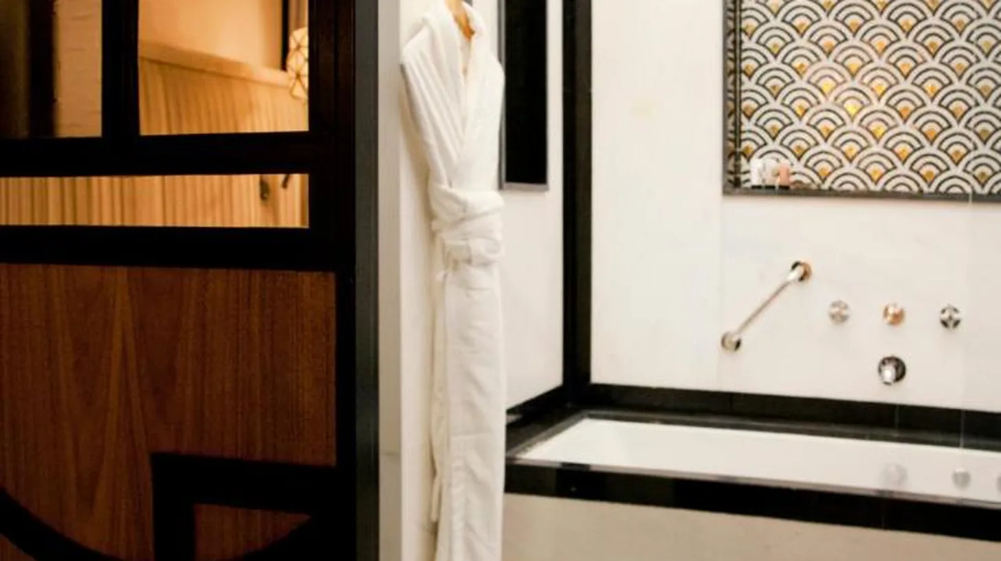 a bathroom with a tub and a robe on a window at Riad Dar Saba - Saba's House in Tangier
