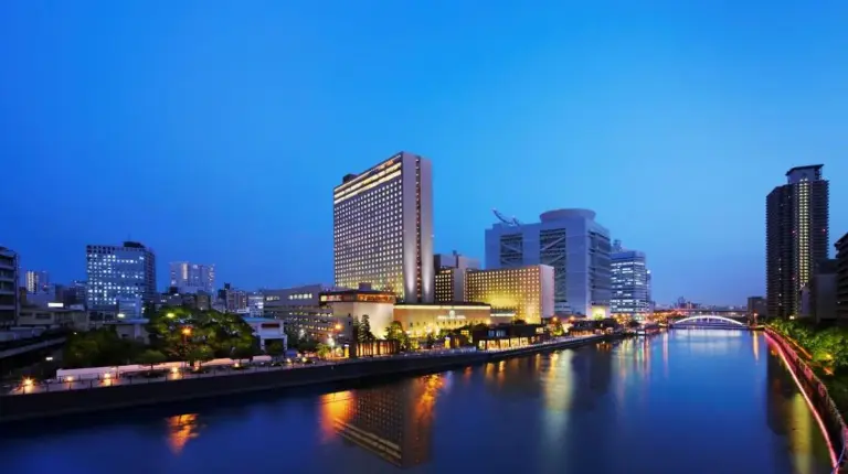 a river in a city at night with tall buildings at RIHGA Royal Hotel Osaka
