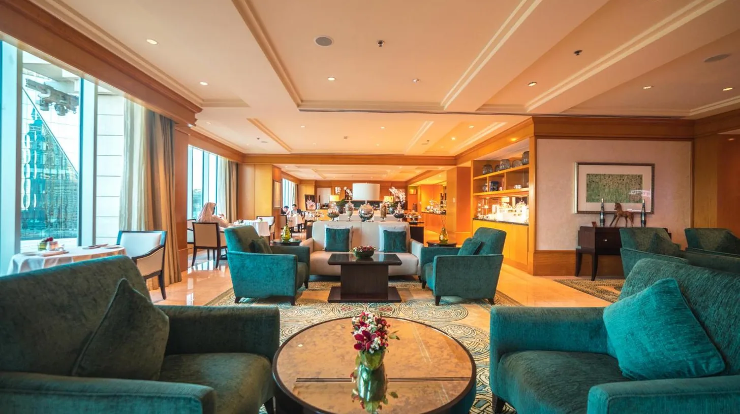 a hotel lobby with blue couches and a restaurant at Ritz Carlton DIFC Downtown Dubai in Dubai