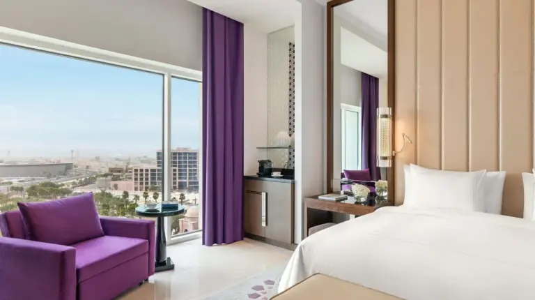 a bedroom with a large bed and a purple chair at Rixos Marina Abu Dhabi in Abu Dhabi