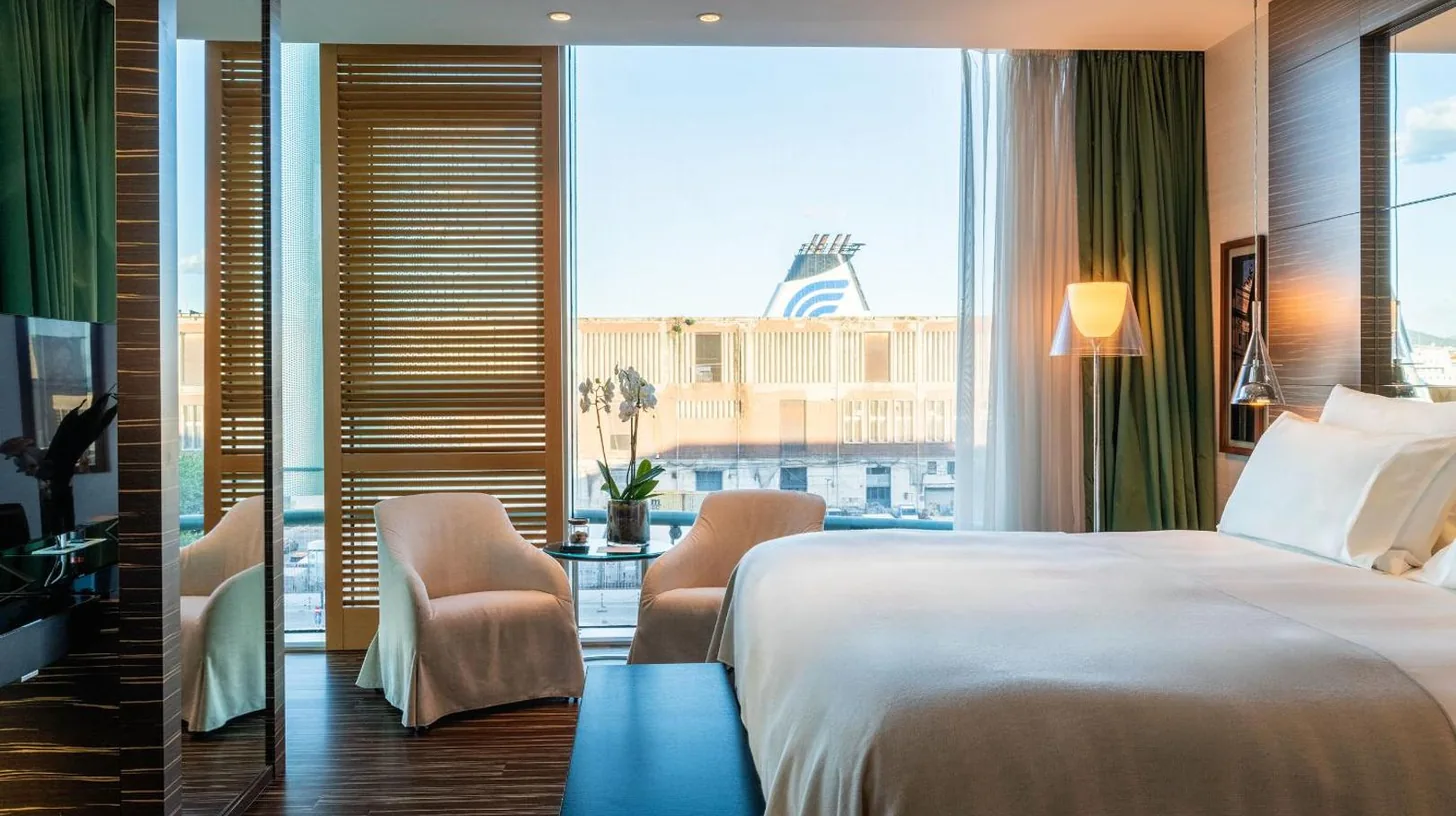 une chambre d'hÃ´tel avec un lit et une grande fenÃªtre au ROMEO Napoli Ã  Naples